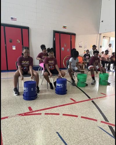 Students seated with buckets for a drum circle activity during camp